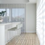 A photo of a kitchen area, with 3 high chairs on the side. The room is well lit.