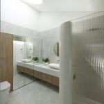 A photo of a bathroom area, with a toilet and shower. There is a sink in the background.