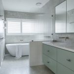 A photo of a bathroom, with a large tub and shower in the back. There is a sink in the foreground.