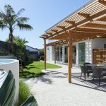 A photo of a wooden patio area, with a table and chairs under it.