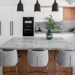 A photo of a kitchen area, with a stone benchtop table and plant.