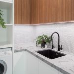 A photo of a laundry area, with a washing machine, a sink and some plants.