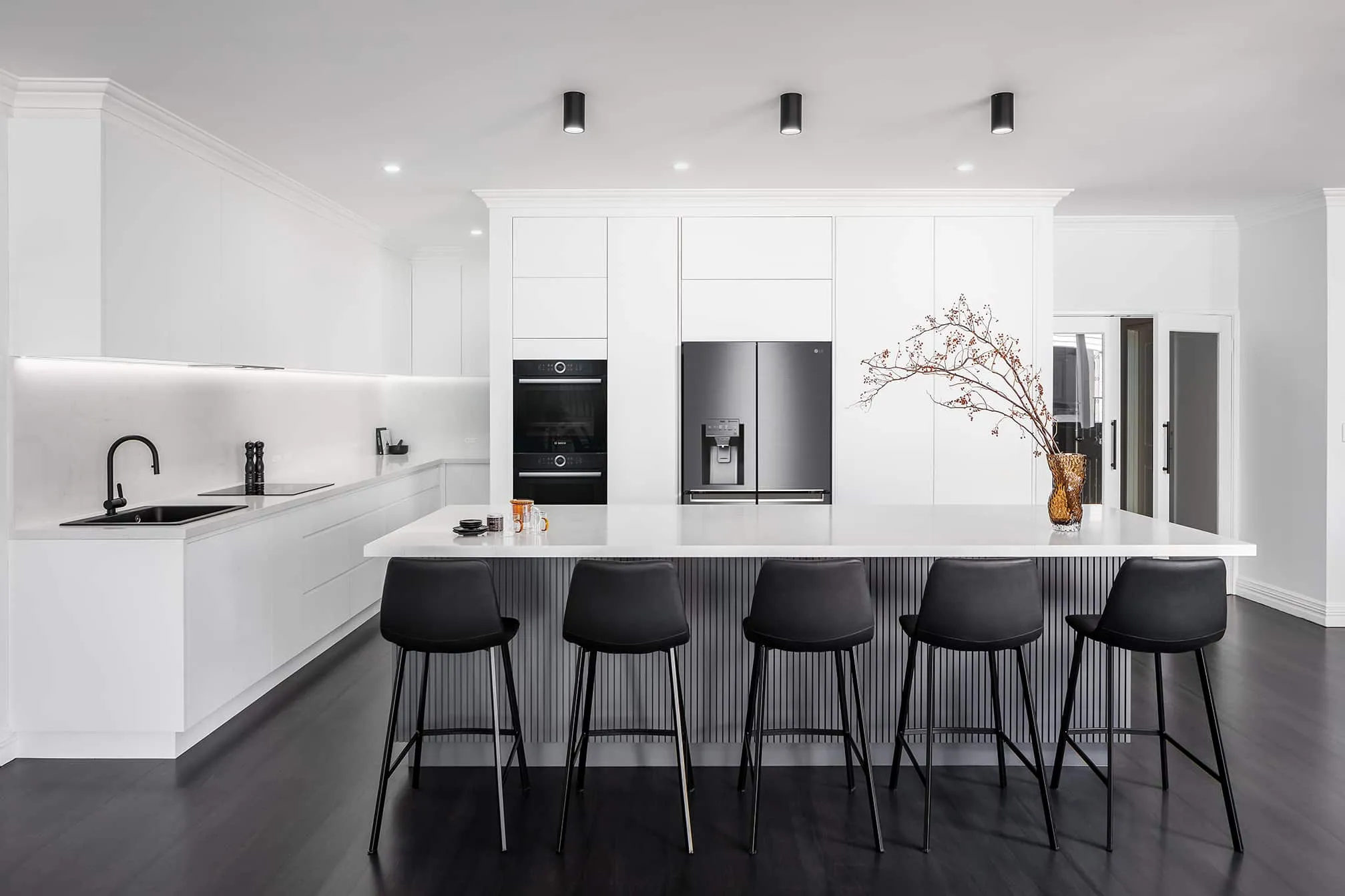 A photo of a kitchen, with black floors, white tables and black chairs.