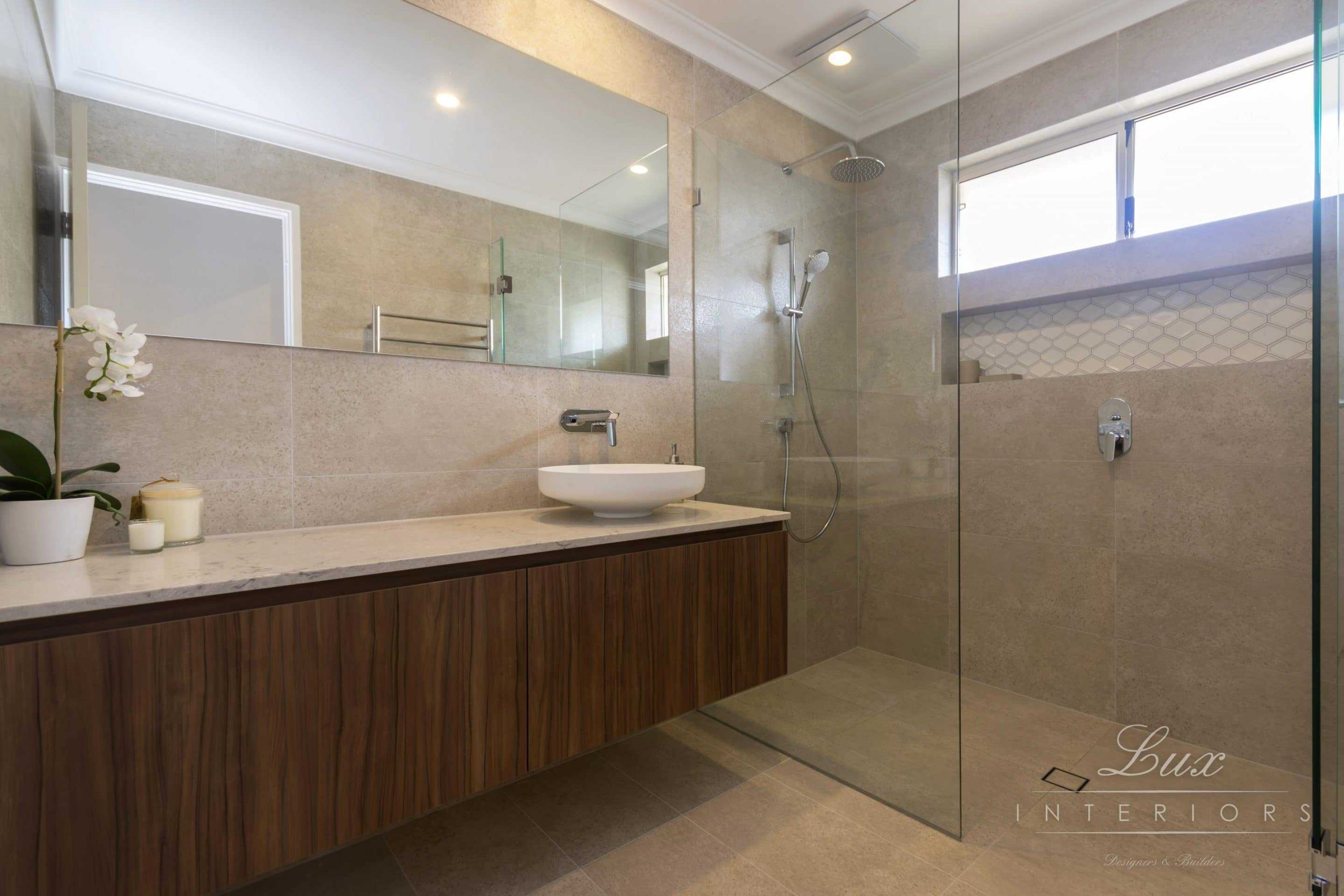 A photo of a bathroom area with a large shower and sink, a large mirror sitting above.