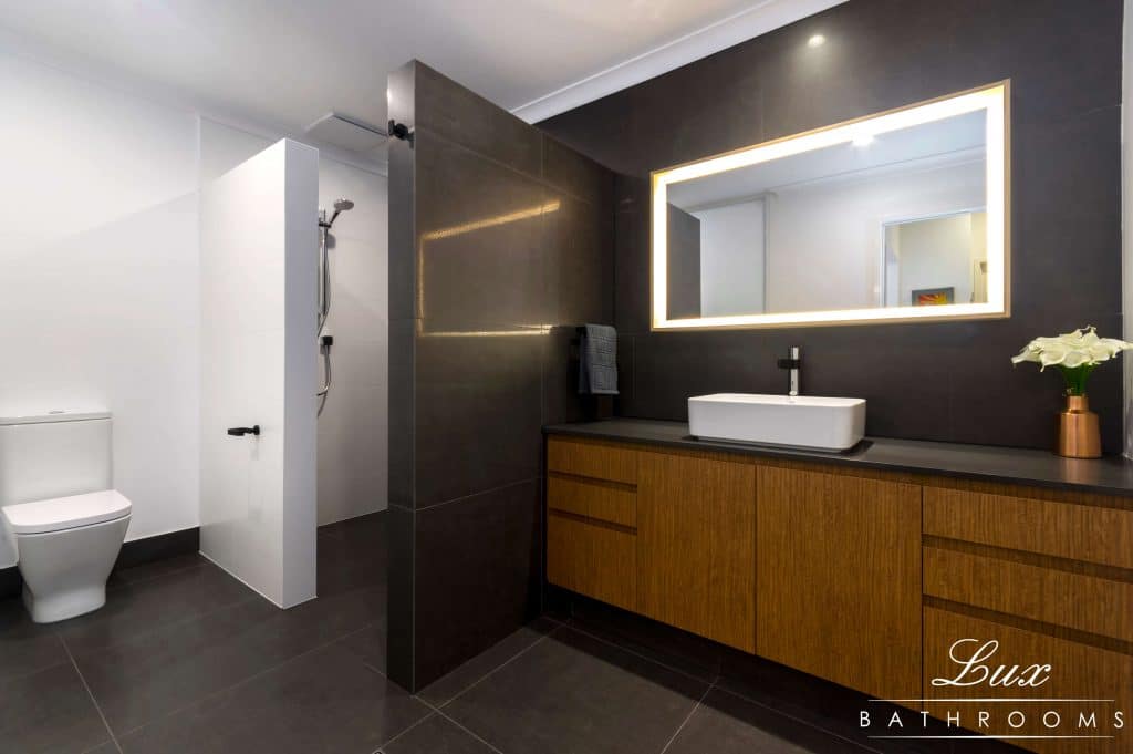 A photo of a Lux Interiors bathroom, with a toilet, shower and sink.