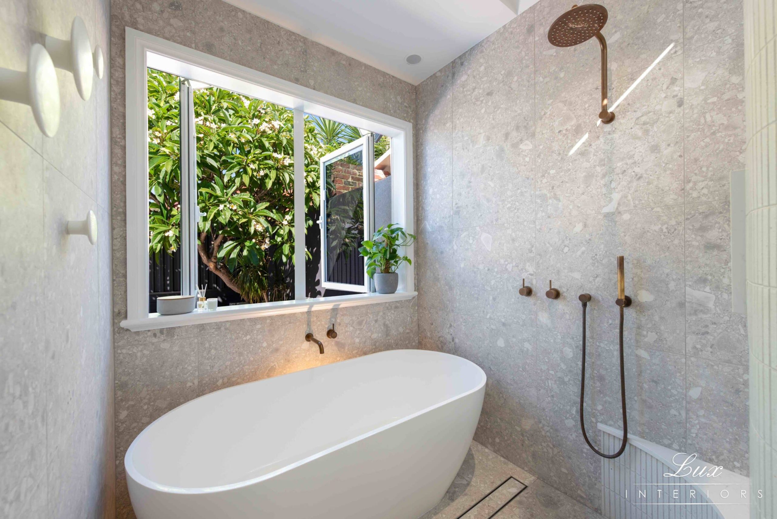 A well-lit bathroom with large open window and deep bath