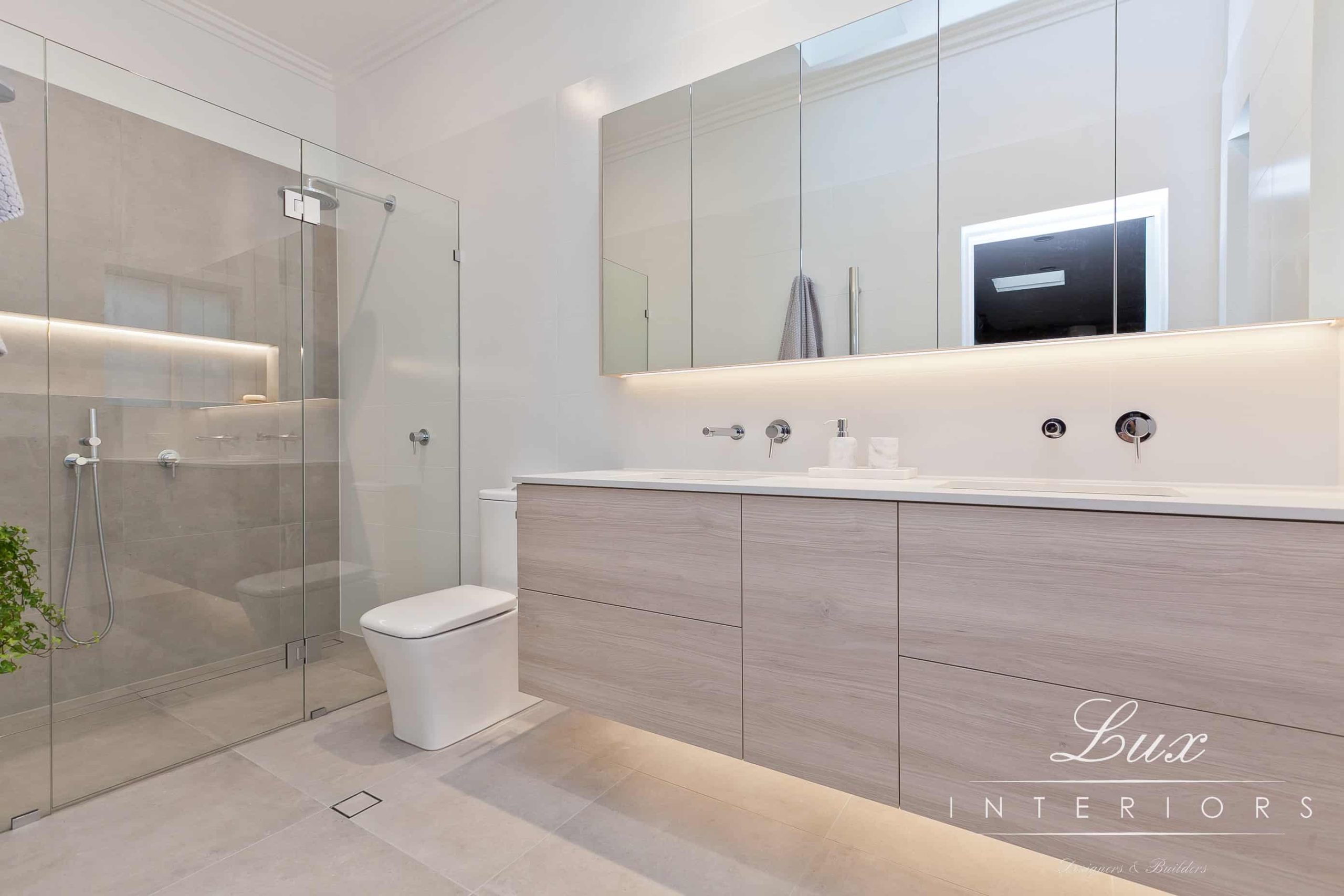 A photo of a bathroom, with a large shower, mirror, sink and toilet.