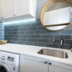 A photo of a laundry area, with a sink, washing machine and dryer.