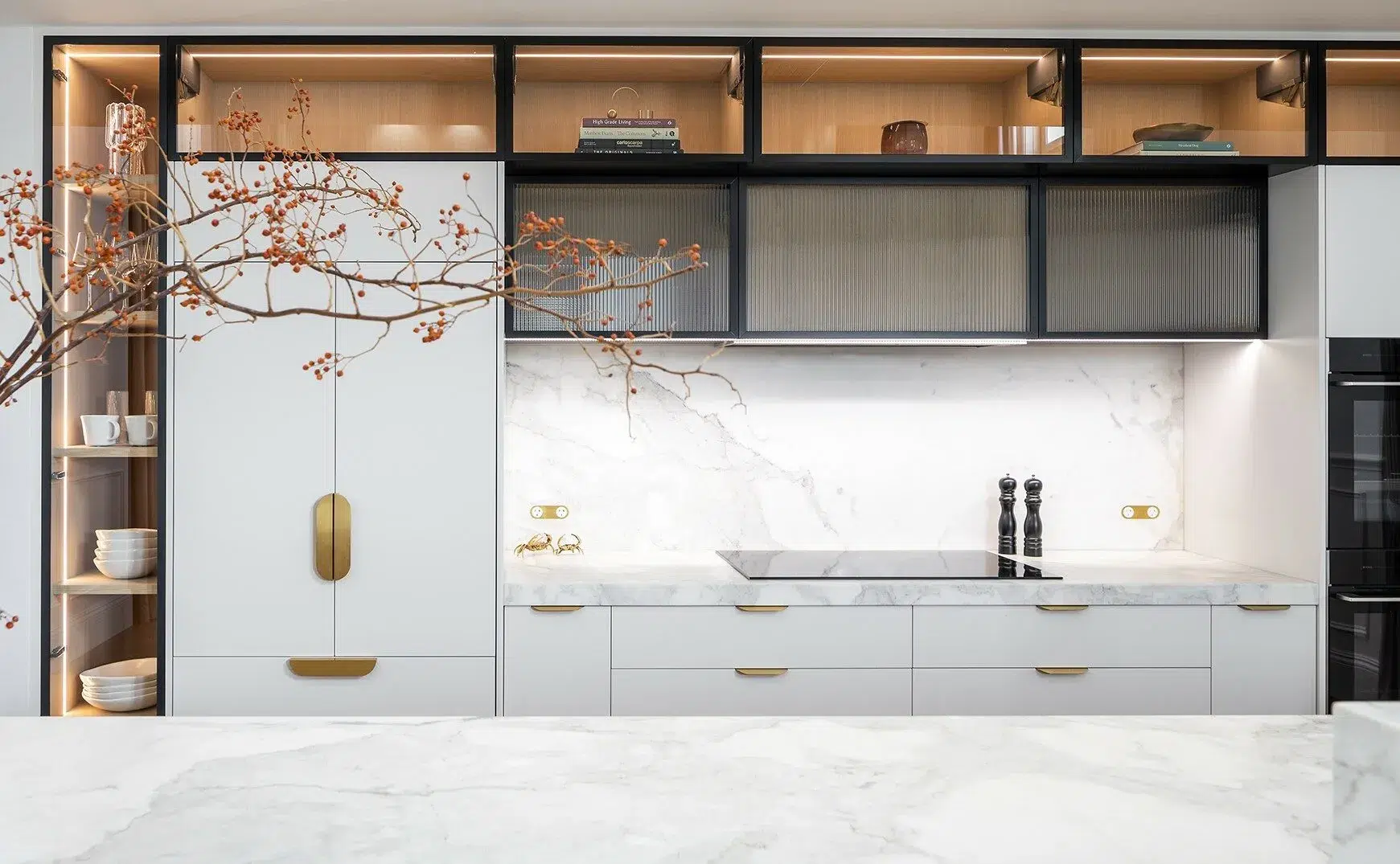 A photo of a kitchen, with a wabi-sabi, japanese feel to it, with white marble tables and black cabinets.