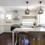 A photo of a kitchen, with wood floors and white tables.