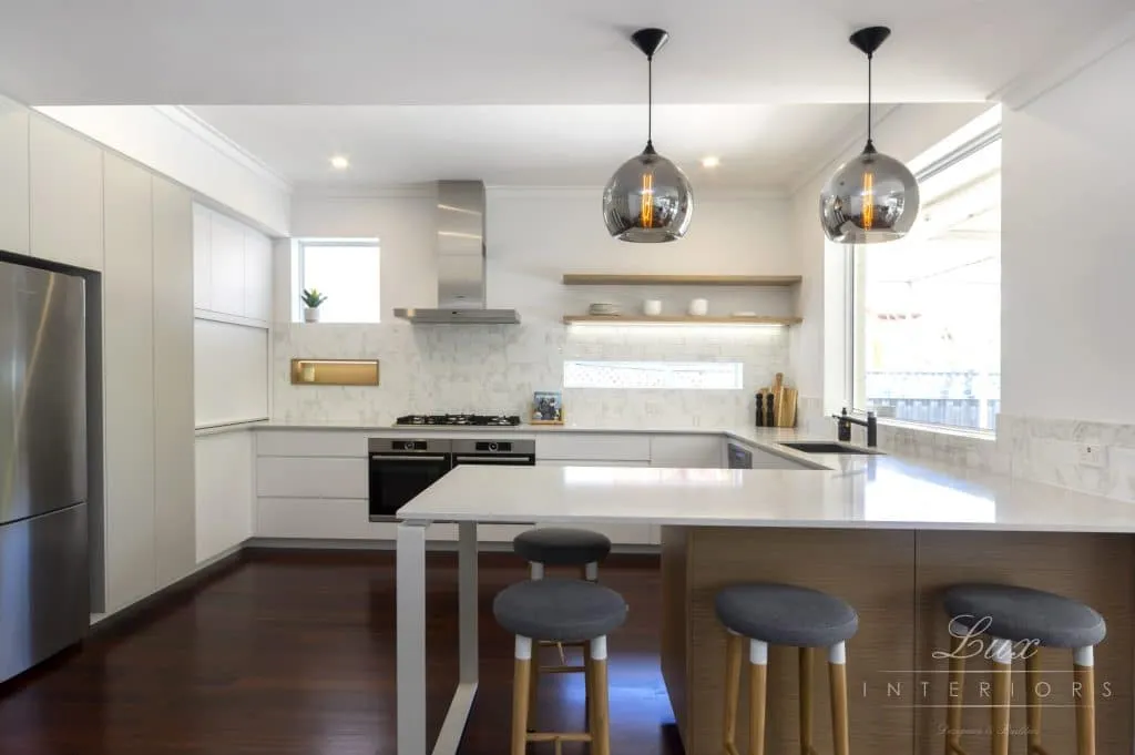 A photo of a kitchen, with wood floors and white tables.