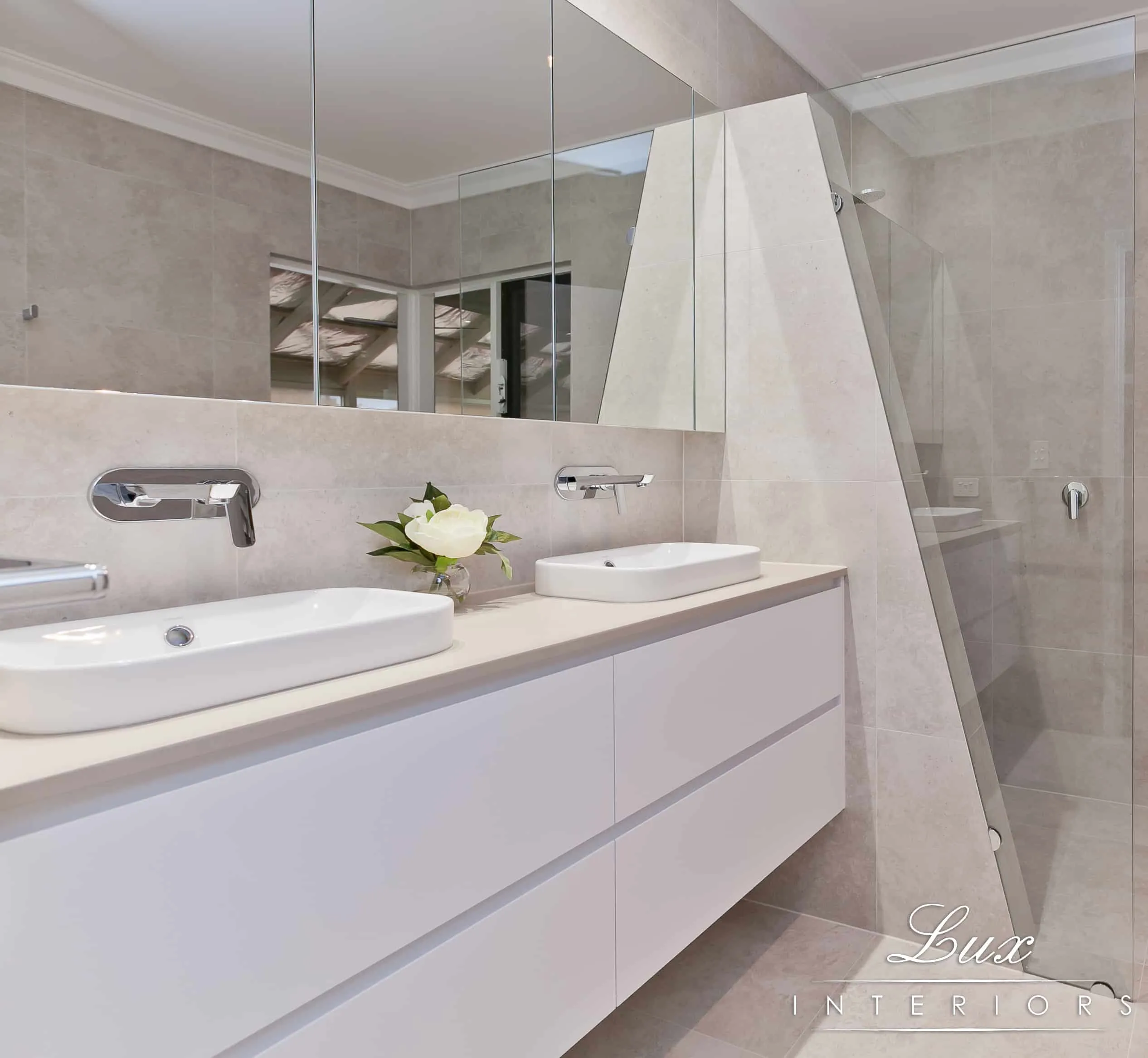 A photo of a bathroom with dual sinks, large mirror and shower.