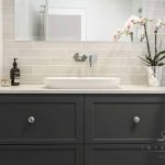 A photo of a white and black bathroom, with a sink and mirror.