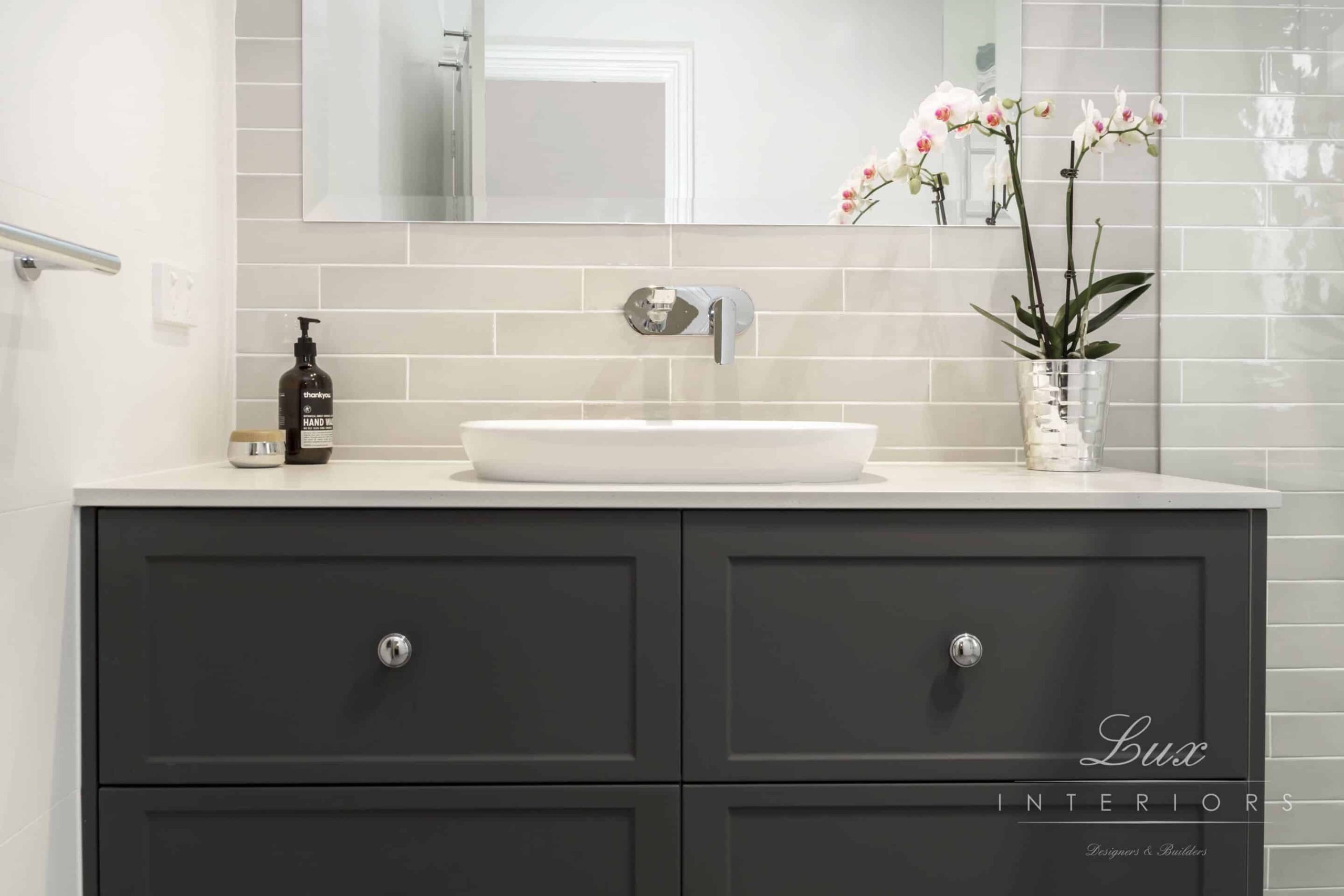 A photo of a white and black bathroom, with a sink and mirror.