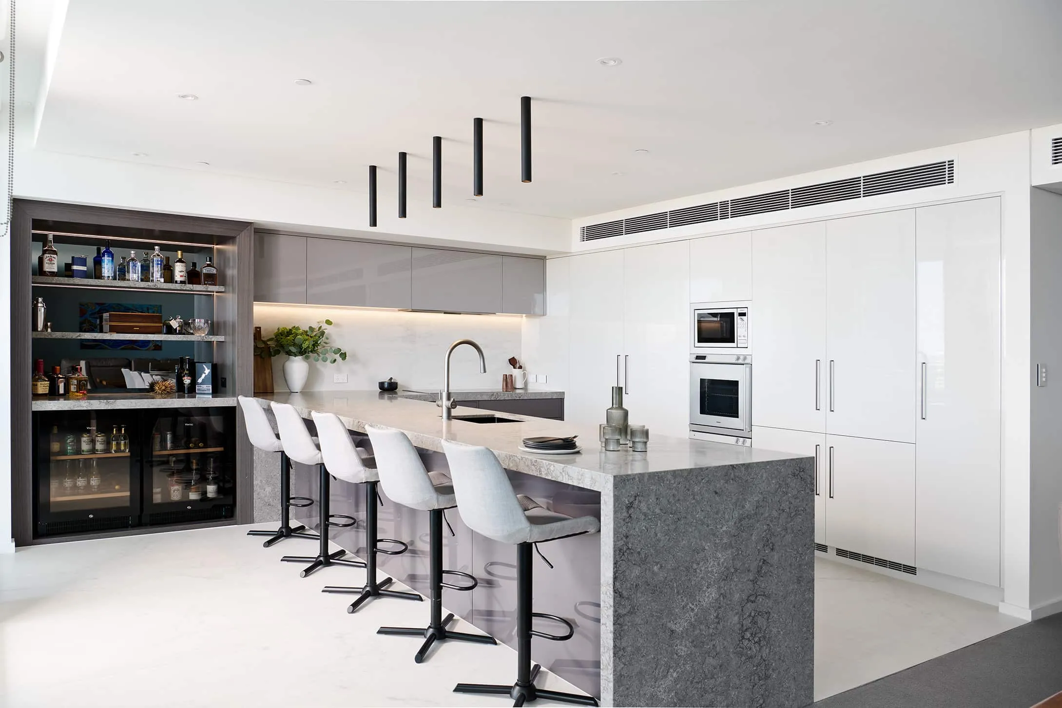 A photo of a kitchen, with a granite grey table, kitchen sink and bar.