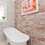 A photo of a bathroom with a bathtub and a full brick wall in the background.