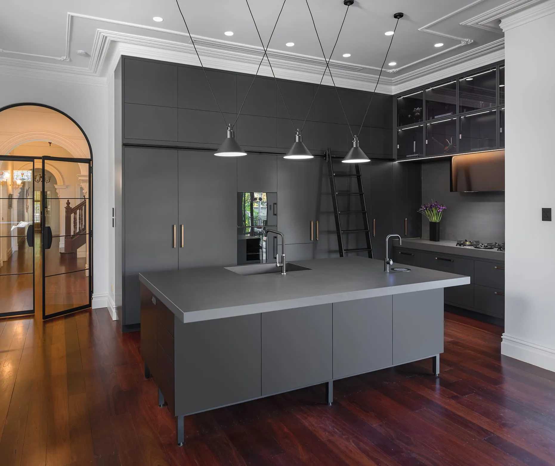 A photo of a kitchen, all black, with a kitchen island table and cabinets in the background.