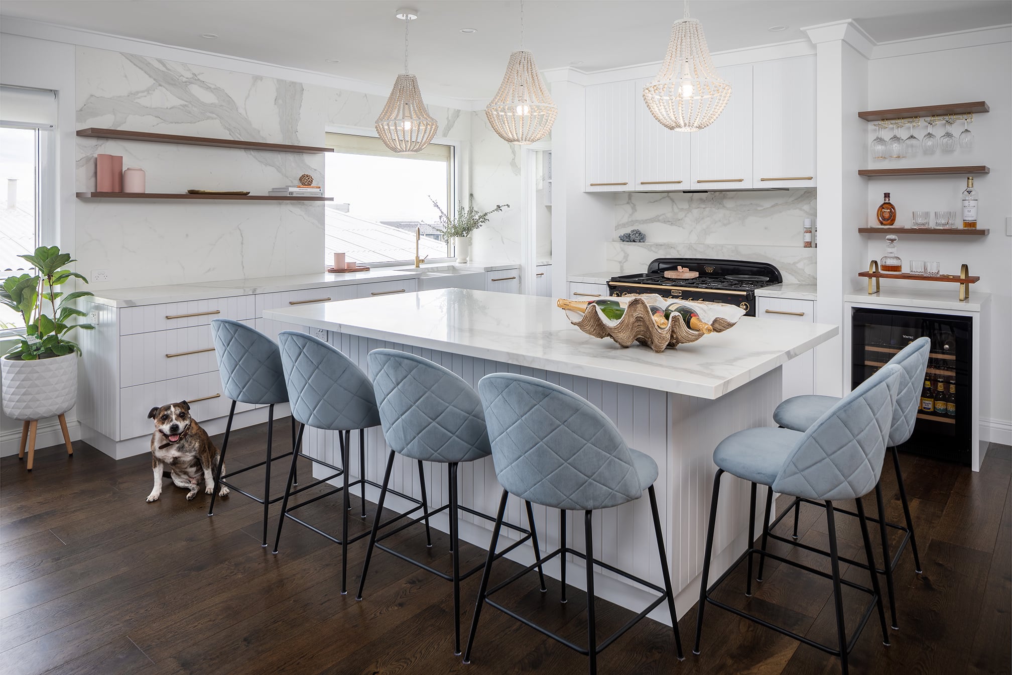 A photo of a Lux Interiors kitchen, with a dog sitting in the corner and a beautiful table top and chairs.