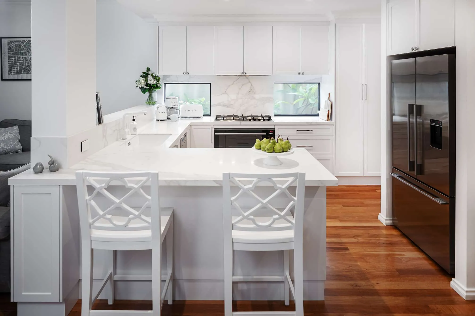 A photo of a kitchen, with an L shaped kitchen island, black fridge and stovetop.