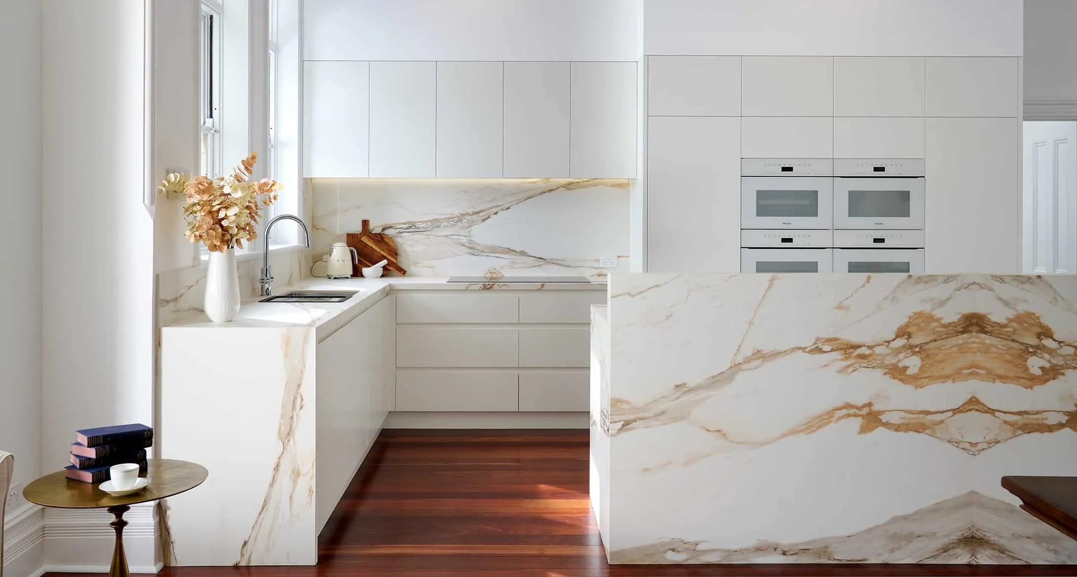 A photo of a kitchen, with stone bench-tops and a gold look & feel.