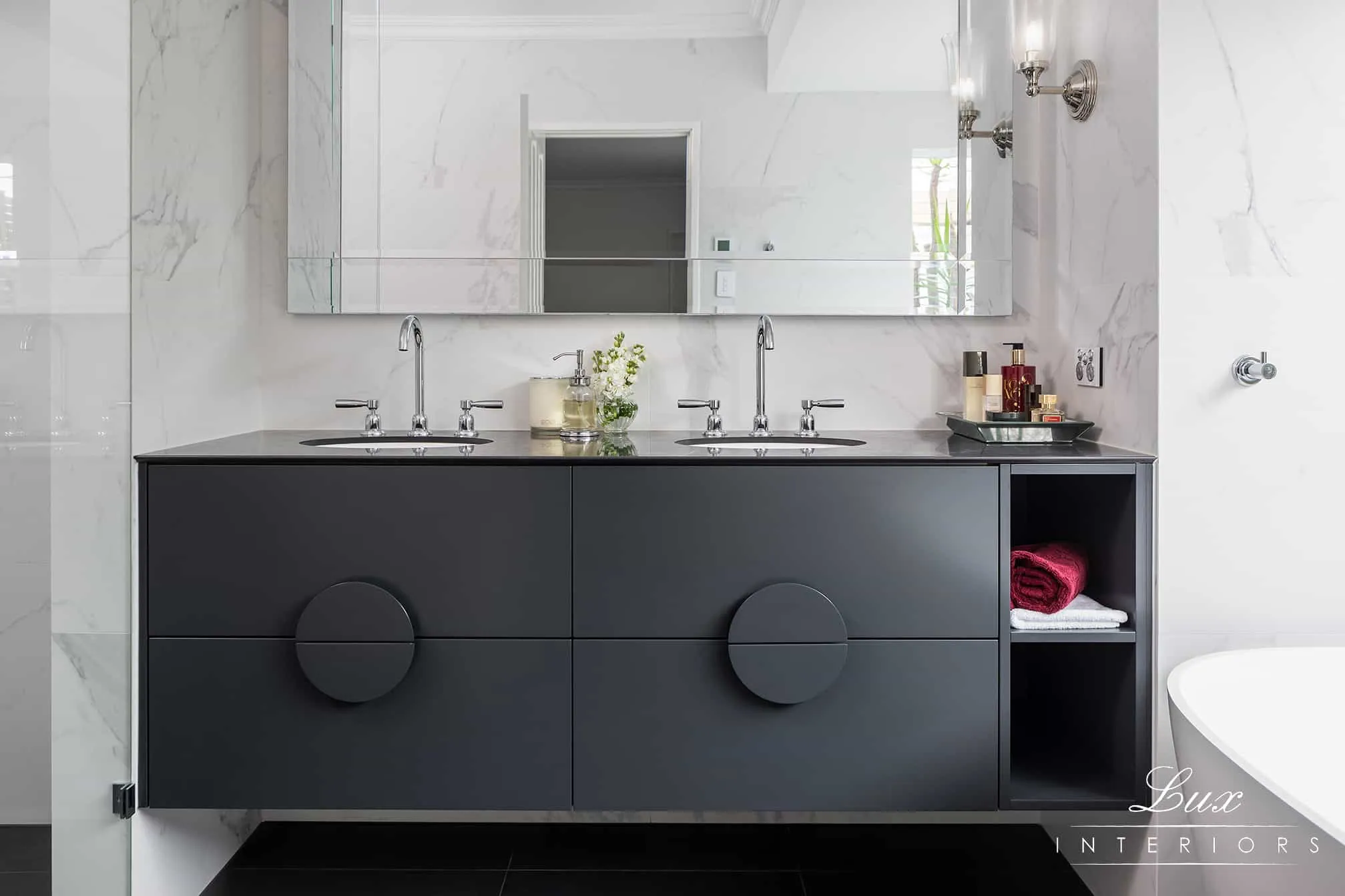 A photo of a bathroom with a black sink, large mirror, with bath and showers on each side.