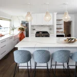 A photo of a kitchen with a table, chairs, stove and various other items you would expect in a kitchen.