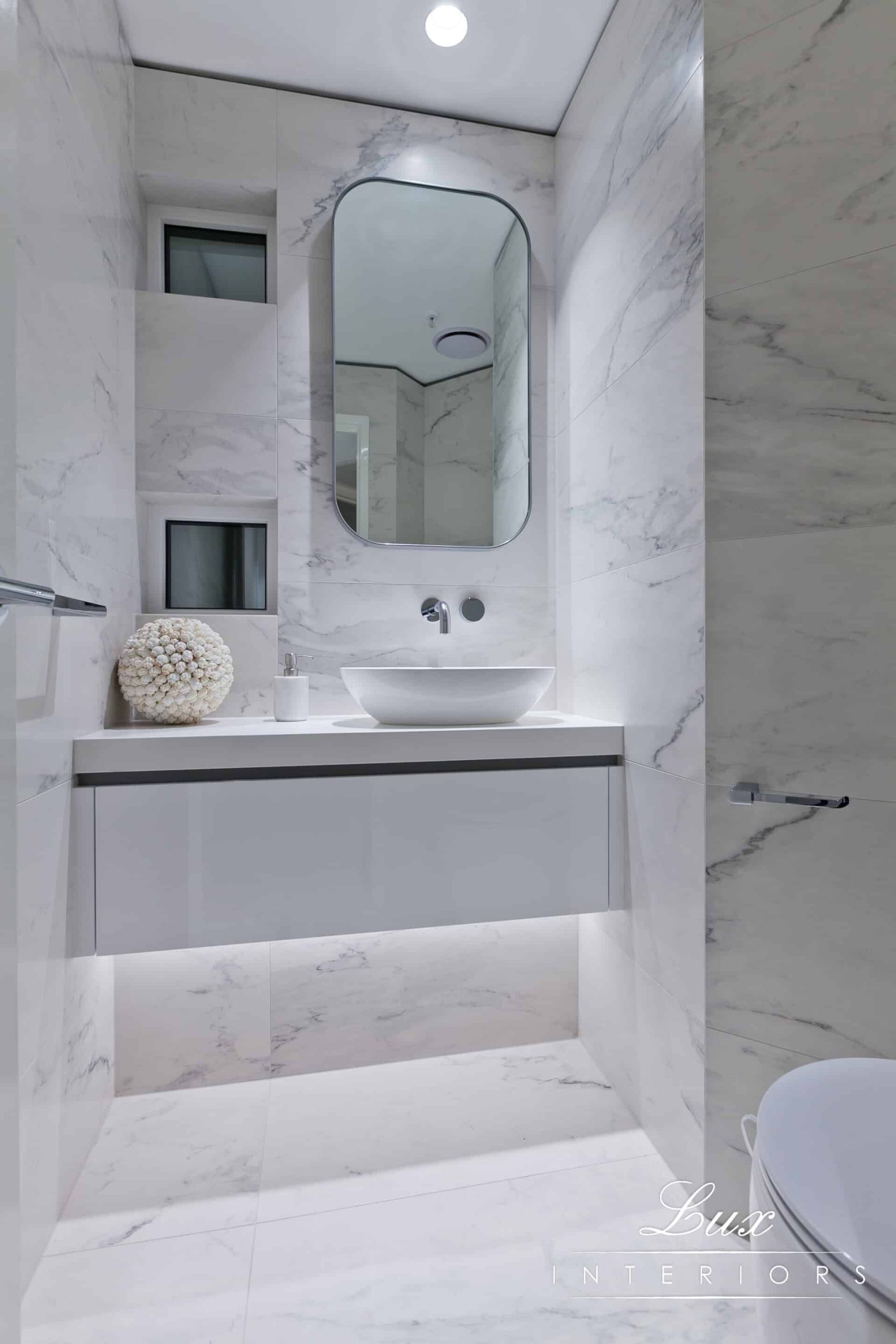 A photo of a bathroom sink, with rounded mirror.