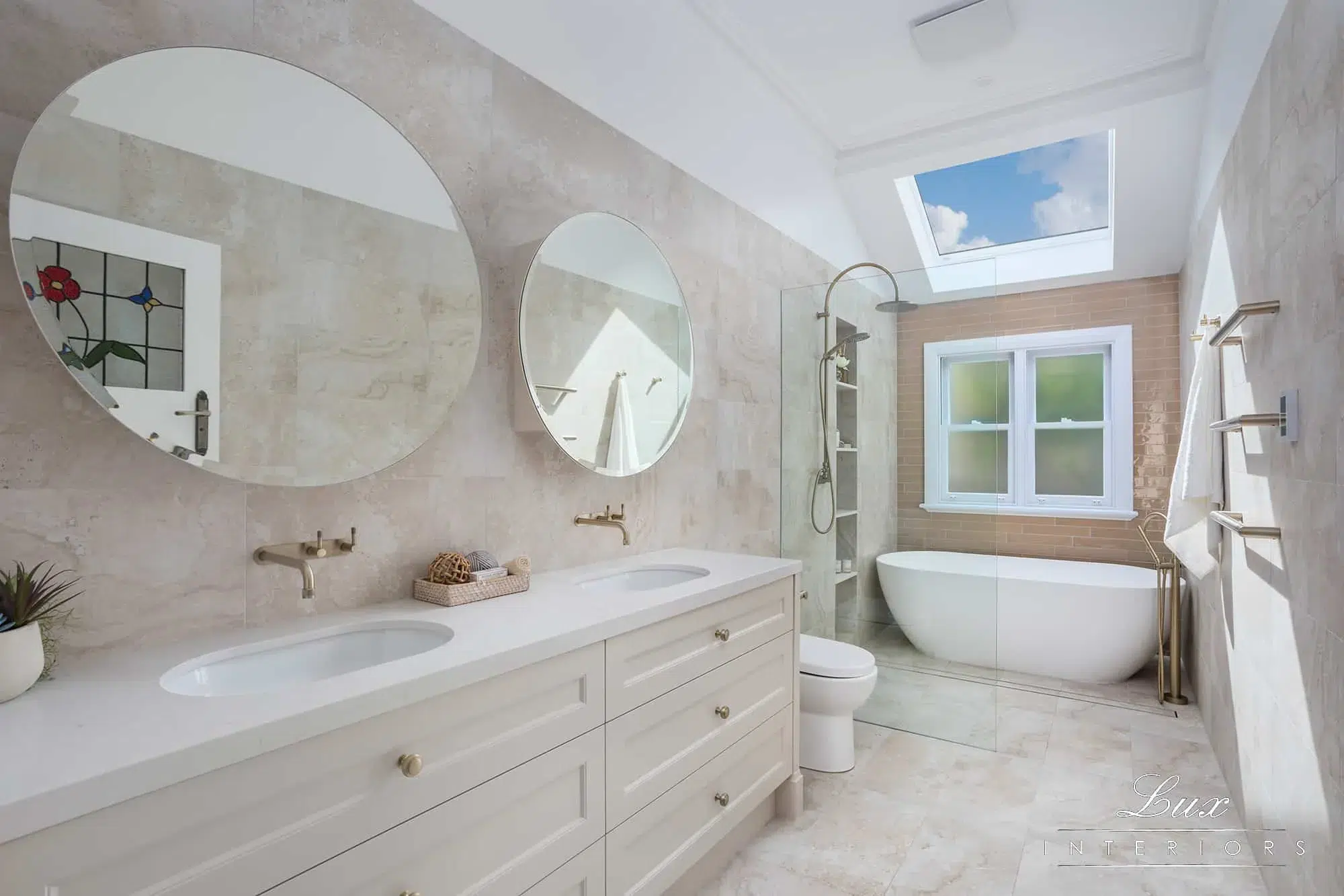 A photo of a bathroom, with a sink, 2 round mirrors, toilet, shower and bathtub.