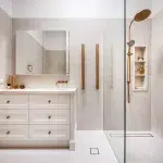 A photo of a bathroom with a sink, mirror and shower.