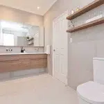 A photo of a bathroom with a large mirror, sink and toilet.