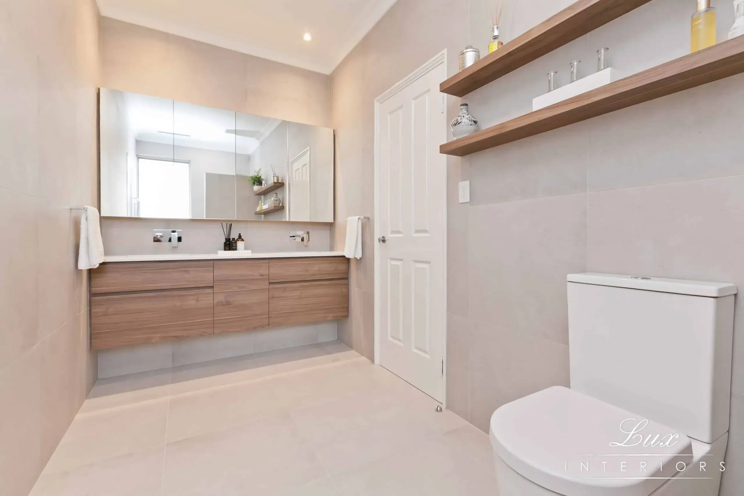 A photo of a bathroom with a large mirror, sink and toilet.